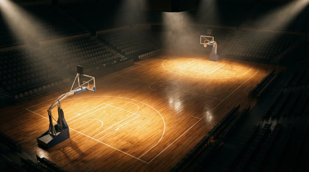 Pavilhão de basquetebol antes de um jogo com luzes acesas e campo vazio visto de cima